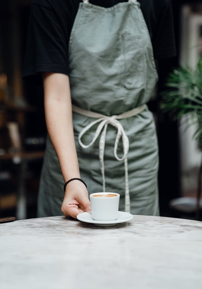 A barista serves a freshly brewed coffee in a modern café, showcasing hospitality and professionalism.